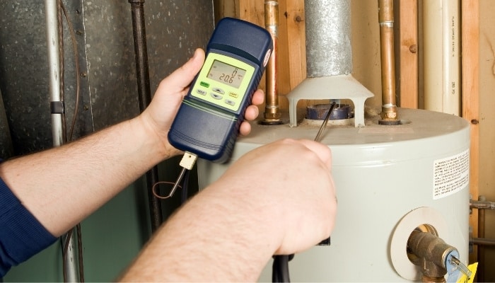 Technician testing a residential water heater during a maintenance inspection.